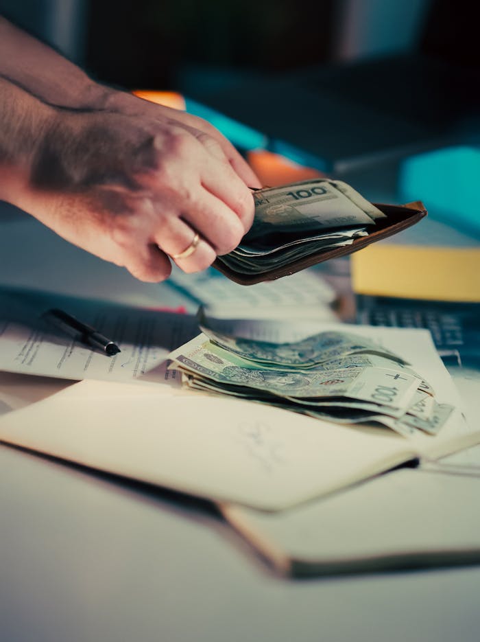 A person manages currency and documents on a desk, illustrating finance and budgeting.